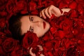 Beauty portrait, young woman in a bath with red rose petals, Top view, model with clean skin, retouching.