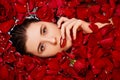 Beauty portrait, young woman in a bath with red rose petals, Top view, model with clean skin, retouching.
