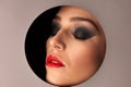 Beauty portreai of a woman with gorgeus makeup thwough circle in gray background