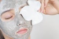 Beauty procedures skin care concept. Young woman applying facial gray mud clay mask to her face .Cosmetic masks. Facial care Royalty Free Stock Photo