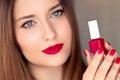 Beauty product, makeup and cosmetics, face portrait of beautiful woman with nail polish, manicure and matching red Royalty Free Stock Photo