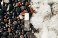 Beauty product transparent bottle on wet beach stones and surrounded by sea foam from the right. Fresh ocean scented Royalty Free Stock Photo