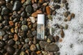 Beauty product transparent bottle on wet beach stones and surrounded by sea foam from the right. Fresh ocean scented Royalty Free Stock Photo