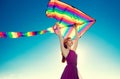 Beauty redhead girl with flying colorful kite over blue sky