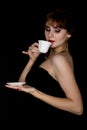 Beauty retro female model with professional makeup, drinking coffee or tea. fashion vintage woman on a dark background Royalty Free Stock Photo