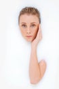 Beauty rising to the surface. Studio shot of an attractive womans face and arm emerging from a milky liquid.