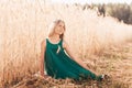Beauty Romantic girl outdoors. Beautiful teen model girl in green dress on the field in sunlight. Blowing long blond hair.  Glow Royalty Free Stock Photo