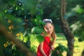 Beauty Girl Outdoors. Beautiful Teenage Model girl in Red Dress is sitting on the garden in Sun Light. Blowing Long Hai Royalty Free Stock Photo