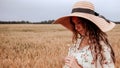 Beauty romantic girl outdoors. Happy young woman in sun hat in summer wheat field at sunset. Copy space, sunset, flare Royalty Free Stock Photo