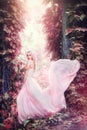 Beauty romantic young woman in long chiffon dress with gown posing in fantasy misty forest. Beautiful happy bride model girl