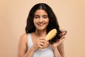 Beauty Routine. Attractive happy indian woman brushing her curly hair with comb Royalty Free Stock Photo