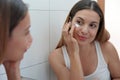 Beauty routine at home. Portrait of beautiful girl applying cream under eye with finger. Dark circles and anti-wrinkle concept Royalty Free Stock Photo