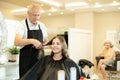 In beauty salon, elderly man makes styling curls for young girl client Royalty Free Stock Photo