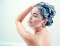 Beauty model girl washing her long black hair with a shampoo