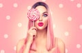 Beauty model woman with trendy pink hairstyle and beautiful makeup holding lollipop candy