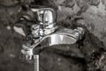Beauty of shiny metal chrome surface on a bathroom tap with water drops on it and concrete wall background as modern interior Royalty Free Stock Photo