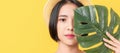 Beauty shot of Asian woman holding green leaves to touch the face on the orange background. Royalty Free Stock Photo