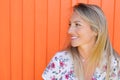 Beauty side profile portrait of blonde woman with long hair looking aside on orange wooden background