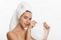 Beauty Skin Care Concept - Beautiful Caucasian Woman applying paper sheet mask on her face white background.