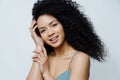 Beauty, skin care concept. Beautiful tender young woman with Afro hair has healthy well cared skin, touches hair, looks positively