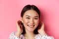 Beauty and skin care concept. Close-up of adorable smiling asian woman tuck hair behind ears, blushing and gazing at Royalty Free Stock Photo