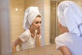 Beauty, skin care and people concept. Smiling young woman washing her face with facial cleansing sponge at bathroom Royalty Free Stock Photo