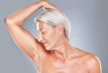 Beauty, skincare and anti aging with a senior woman in studio on a gray background to smell her armpit. Wellness, health