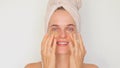 Beauty and skincare regimen. Cosmetic facial treatment. Smiling delighted woman wearing bath towel carefully places under-eye