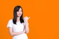 Beauty smiling brunette Asian woman pointing away and smiling and looking at the camera over color background Royalty Free Stock Photo