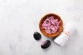 Beauty, spa background with massage stone and flowers in bowl on white table top view. Relaxation and wellness concept. Flat lay Royalty Free Stock Photo