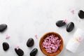 Beauty, spa background with massage stone and flowers in bowl on white table top view. Relaxation and wellness concept. Flat lay