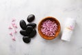 Beauty, spa background with massage stone, towel and flowers in bowl on white table from above. Relaxation and wellness concept.