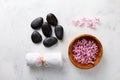 Beauty, spa background with massage stone, towel and flowers in bowl on white table top view. Relaxation and wellness concept.