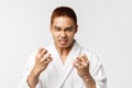 Beauty, spa and leisure concept. Portrait of angry, hateful asian man in bathrobe look with hate and anger camera