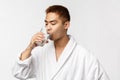 Beauty, spa and technology concept. Portrait of young handsome healthy asian man, drinking water from glass and wear Royalty Free Stock Photo