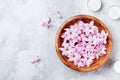 Beauty, spa and wellness composition of perfumed pink flowers water in wooden bowl and candles on stone table. Aromatherapy. Royalty Free Stock Photo