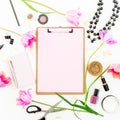 Beauty space with clipboard, notebook, cosmetics, flowers and accessories on white background. Flat lay, top view.