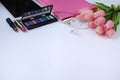 Beauty stuff. Makeup background. Aspects of makeup. Folder, tablet, tulips flowers, headphones, lipsticks and eye shadows on the t