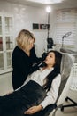 Beauty stylist making lips shape before permanent makeup procedure at the cosmetic salon.