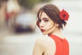 Beauty teen. Young woman with red lips makeup on cute young face and roses in brunette hair posing outdoors, summer day Royalty Free Stock Photo