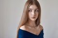 Beauty theme: portrait of a beautiful young girl with freckles on her face and wearing a blue dress on a white background in Royalty Free Stock Photo