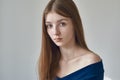 Beauty theme: portrait of a beautiful young girl with freckles on her face and wearing a blue dress on a white background in