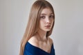 Beauty theme: portrait of a beautiful young girl with freckles on her face and wearing a blue dress on a white background in Royalty Free Stock Photo