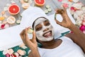 Beauty treatment. Top view of beautiful young African woman lying with pieces of cucumber on her face in spa Royalty Free Stock Photo