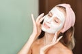 Beauty Treatments. Young woman is applying a mask, cream on her face close-up. Facial skin care portrait of a beautiful girl with Royalty Free Stock Photo