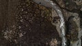 Beauty of wild nature, aerial top view of a narrow curving stream flowing along dry field. Shot. Soil with deep cracks