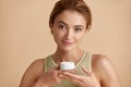 Beauty woman applying face cream. Closeup of female model holding cream bottle Royalty Free Stock Photo