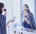 Beauty woman applying makeup. Beautiful girl looking in the mirror and applying cosmetic with a big brush Royalty Free Stock Photo