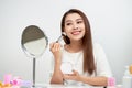 Beauty woman applying makeup. Beautiful girl looking in the mirror and applying cosmetic with a big brush. Girl gets blush on the Royalty Free Stock Photo