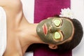 Beauty Woman with clay facial mask  and cucumbers on eyes in beauty spa Royalty Free Stock Photo